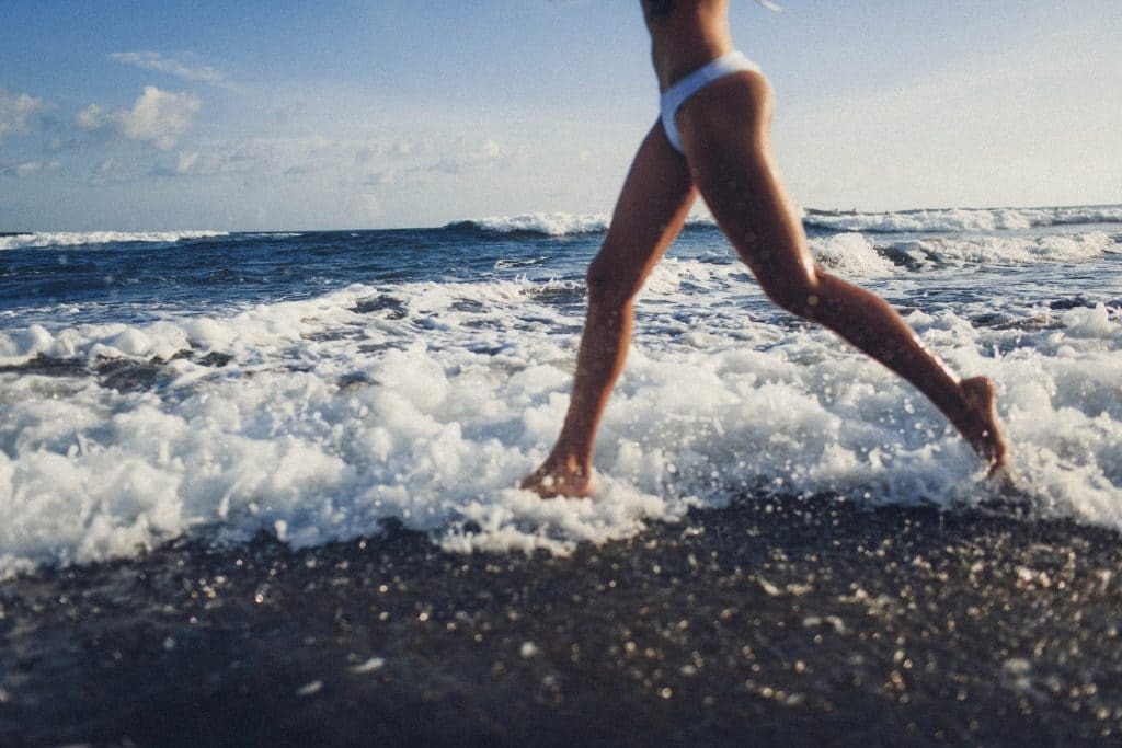 woman in white bathing suit running on the beach